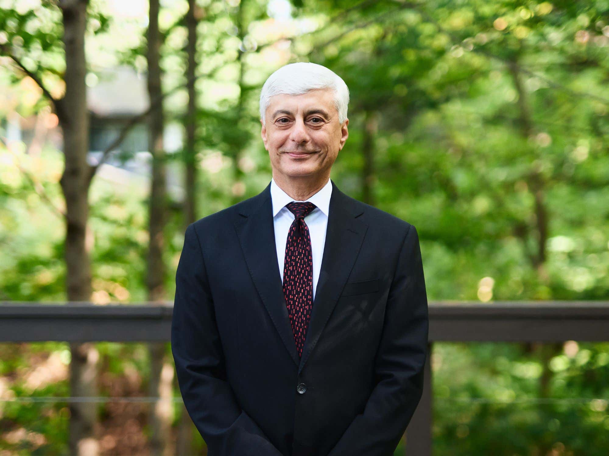 Portrait of Dr. Patrick Safieh standing on a bridge in a wooded area.